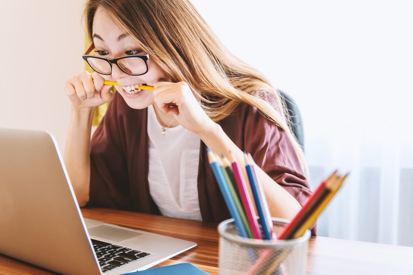 Frustrated creator biting a pencil in front of a laptop