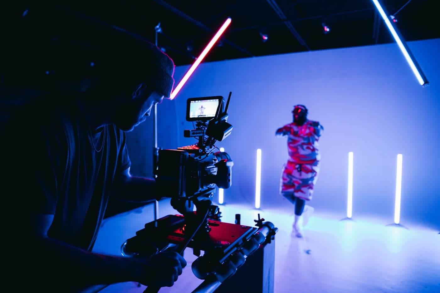 Video camera filming a performer on a neon-lit set